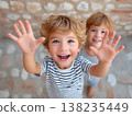 Cheerful child raising hands with open palms, beaming smile radiating pure happiness  138235449