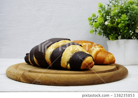 Fresh and tasty croissants on wooden plate 138235853