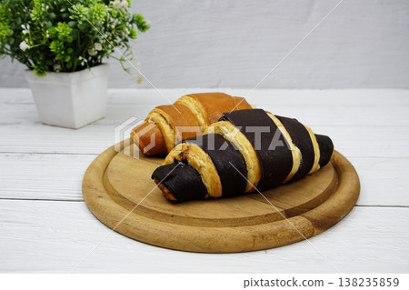 Fresh and tasty croissants on wooden plate 138235859