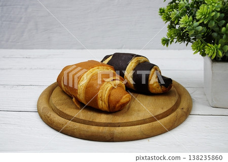 Fresh and tasty croissants on wooden plate 138235860