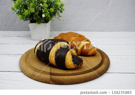 Fresh and tasty croissants on wooden plate 138235865