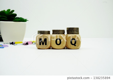Stack of coins with wood blocks with "MOQ (Minimum Order Quantity)" Financial concept 138235894