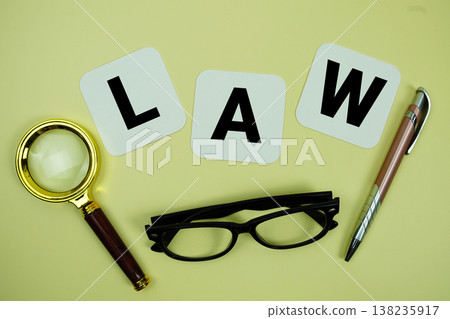 LAW alphabet letters with magnifying glass, eye glasses and pen on yellow background LAW alphabet letters with magnifying glass, eye glasses and pen on yellow background 138235917