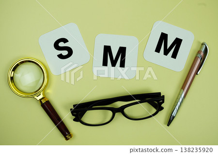 SMM (Social Media Marketing) alphabet letters with magnifying glass, eye glasses and pen on yellow background 138235920