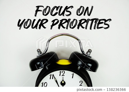 Focus On Your Priorities text with alarm clock flat lay on white background Focus On Your Priorities text with alarm clock flat lay on white background 138236366