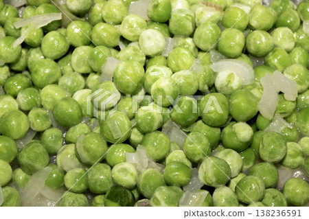 Close up of petit pois peas being fried with chopped garlic in a pan Close up of petit pois peas being fried with chopped garlic in a pan 138236591