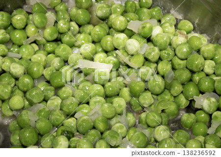 Close up of petit pois peas being fried with chopped garlic in a pan 138236592