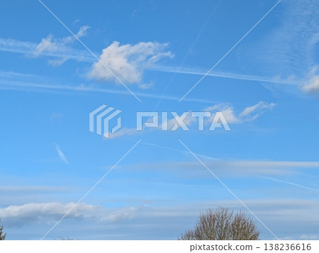 Beautiful blue summer air with fluffy white clouds and chem trail lines across the sky 138236616