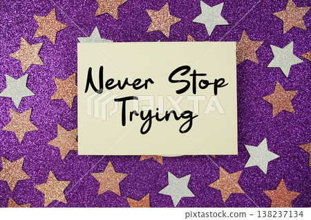"Never Stop Trying" quotes on paper card with purple glitter background with pink and white stars "Never Stop Trying" quotes on paper card with purple glitter background with pink and white stars 138237134