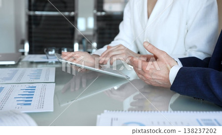Business professionals in a meeting analyzing financial charts and reports on a laptop and documents, pointing at data while planning investment strategy and business growth in a modern office 138237202