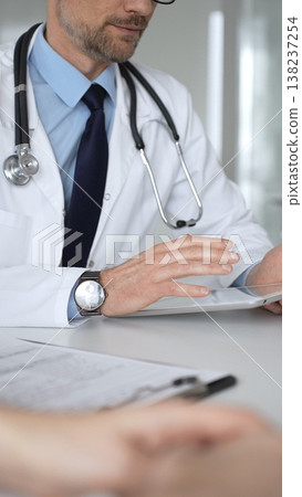 Doctor man interacting with patient during consultation, using digital tablet for modern medical healthcare technology. Medicine, healthcare and science concept 138237254