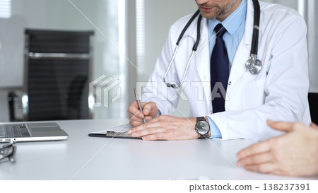 Doctor discussing medical information and treatment plans with a patient during a healthcare consultation in a clinic office. Medicine, healthcare and science concept Doctor discussing medical information and treatment plans with a patient during a healthcare consultation in a clinic office. Medicine, healthcare and science concept 138237391
