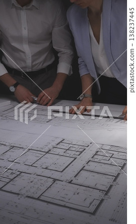 Architects collaborating on a modern house design, working with a scale model and engineering blueprints on a desktop. Concept of architecture and business in low key lighting Architects collaborating on a modern house design, working with a scale model and engineering blueprints on a desktop. Concept of architecture and business in low key lighting 138237445