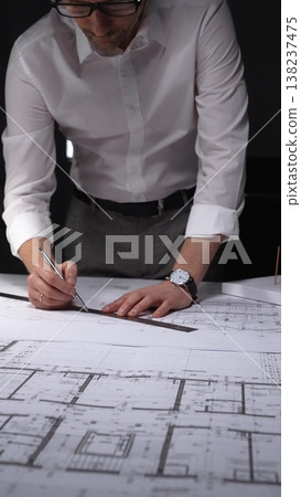 Architect drawing floor plan blueprint with ruler and pen, designing new building construction project. Concept of architecture and business in low key lighting 138237475