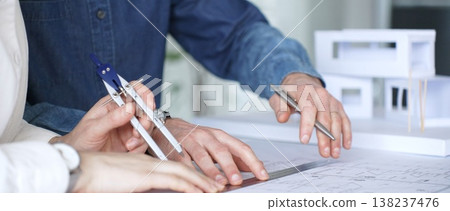 Architects collaborating on architectural plans. Designing modern building models. Drawing blueprints. Engineering innovative residential project solutions Architects collaborating on architectural plans. Designing modern building models. Drawing blueprints. Engineering innovative residential project solutions 138237476