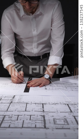 Architect drawing floor plan blueprint with ruler and pen, designing new building construction project. Concept of architecture and business in low key lighting 138237545