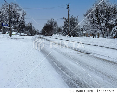冬日雪景,蜿蜒的道路上可以看到積雪覆蓋的居民區街道上的輪胎印。 冬日雪景,蜿蜒的道路上可以看到積雪覆蓋的居民區街道上的輪胎印。 138237786