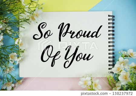 So Proud Of You text written on notepad with flowers decorations flat lay on multicolor pastel background 138237972