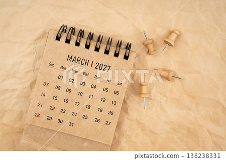 March 2027 desk calendar with wooden thumbtack on brown crumpled paper background. March 2027 desk calendar with wooden thumbtack on brown crumpled paper background. 138238331