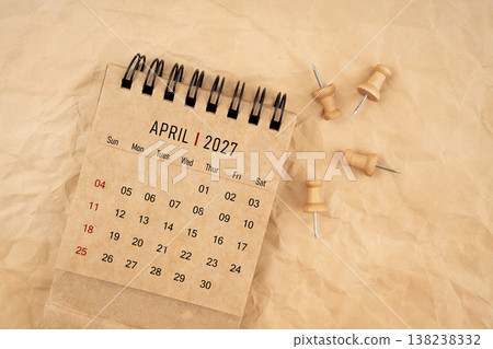 April 2027 desk calendar with wooden thumbtack on brown crumpled paper background. April 2027 desk calendar with wooden thumbtack on brown crumpled paper background. 138238332