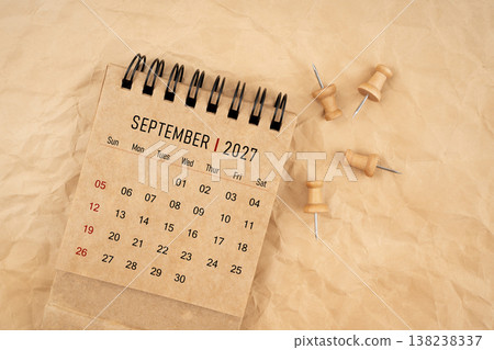 September 2027 desk calendar with wooden thumbtack on brown crumpled paper background. September 2027 desk calendar with wooden thumbtack on brown crumpled paper background. 138238337