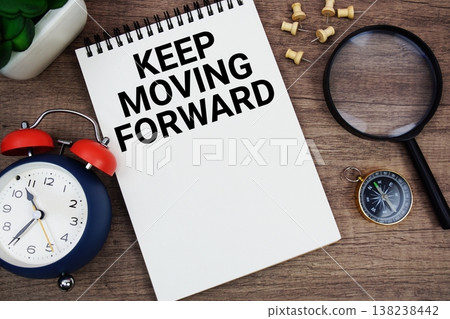 Keep Moving Forward text written on notepad with alarm clock, compass and magnifying glass flat lay on wooden background 138238442