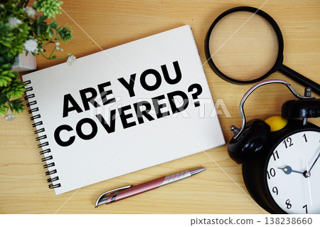 Are You Covered? text written on notepad with alarm clock and magnifying glass flat lay on wooden background 138238660