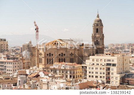 Panoramic view of Malaga Cathedral with its bell tower rising above dense urban rooftops and distant mountains. Malaga, Spain Panoramic view of Malaga Cathedral with its bell tower rising above dense urban rooftops and distant mountains. Malaga, Spain 138239142