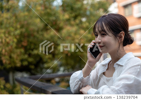 A young woman talking on her cell phone in an outdoor area with trees. A young woman talking on her cell phone in an outdoor area with trees. 138239704