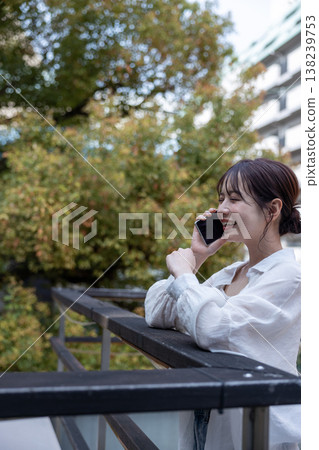 A young woman talking on her cell phone in an outdoor area with trees. A young woman talking on her cell phone in an outdoor area with trees. 138239753