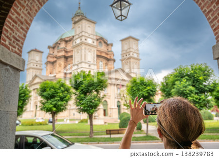 Vicoforte, piedmont, italy. July 21, 2024. Woman capturing the historic sanctuary of vicoforte, a famous baroque church, with smartphone during sightseeing 138239783