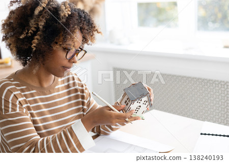female architect or realtor holds mock up of house in her hands, deals with planning. female architect or realtor holds mock up of house in her hands, deals with planning. 138240193