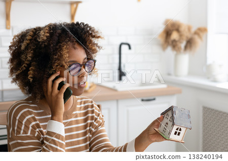 female architect or realtor holds mock up of house in her hands, talks on phone with client. 138240194