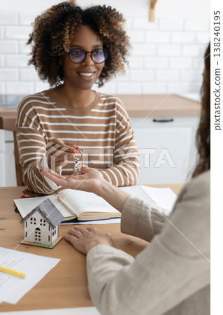 Close-up of happy woman realtor or property owner handing over key to house. Close-up of happy woman realtor or property owner handing over key to house. 138240195