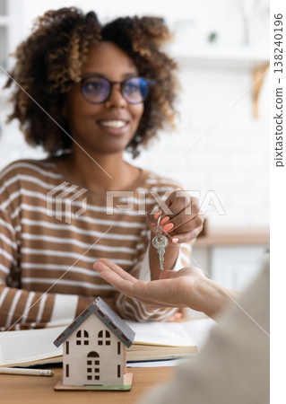Close-up of happy woman realtor or property owner handing over key to house. Close-up of happy woman realtor or property owner handing over key to house. 138240196