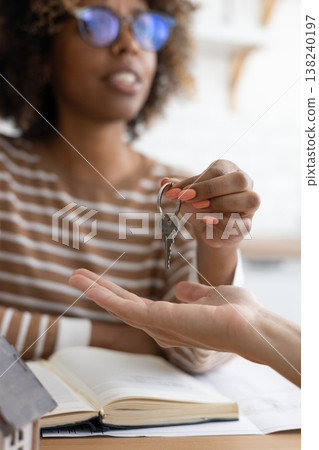 Close-up of happy woman realtor or property owner handing over key to house. Close-up of happy woman realtor or property owner handing over key to house. 138240197