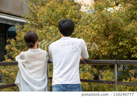 一對年輕男女背影並肩站在陽台上。 一對年輕男女背影並肩站在陽台上。 138240777