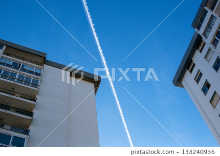 Airplane Contrail in Clear Blue Sky Between Modern Buildings Airplane Contrail in Clear Blue Sky Between Modern Buildings 138240936