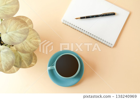 A cup of coffee with notepads and pen on desk. 138240969