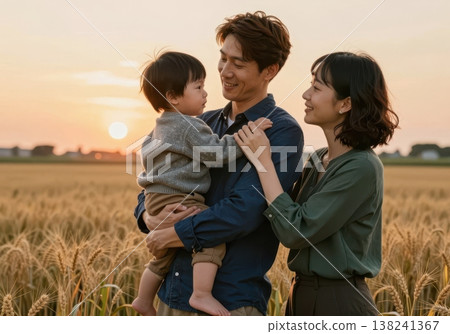 Joyful Asian family portrait at sunset in golden wheat field, father holding baby with mother smiling. 138241367