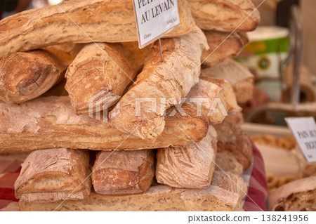 Rustic loaves of bread with a golden crust displayed on a local market table in Aix-en-Provence, a French gastronomic atmosphere Rustic loaves of bread with a golden crust displayed on a local market table in Aix-en-Provence, a French gastronomic atmosphere 138241956