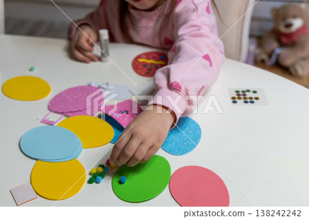 Child hands making festive easter egg craft with glue and foam shapes. Child hands making festive easter egg craft with glue and foam shapes. 138242242