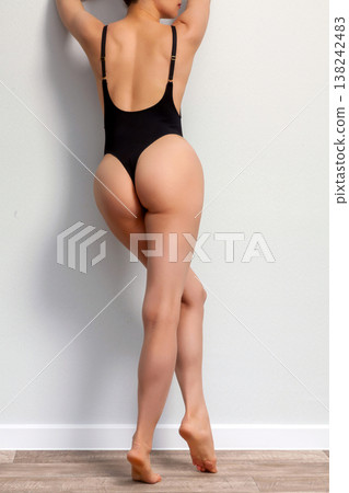 Young adult woman in black lingerie standing by the grey wall Young adult woman in black lingerie standing by the grey wall 138242483