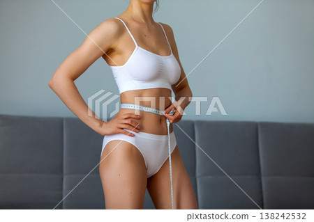 young adult woman measuring her waist young adult woman measuring her waist 138242532