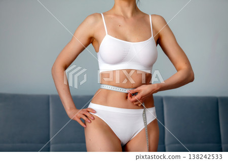 young adult woman measuring her waist young adult woman measuring her waist 138242533