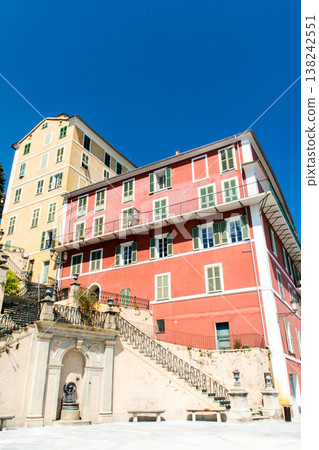 在地中海的法國科西嘉島上，一棟淡紅色粉彩建築沐浴在明媚的陽光下，門是遮光的。 138242551