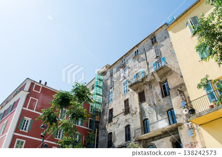 A pastel-colored building with blackout doors bathed in bright sunlight on the French island of Corsica in the Mediterranean Sea. A pastel-colored building with blackout doors bathed in bright sunlight on the French island of Corsica in the Mediterranean Sea. 138242573