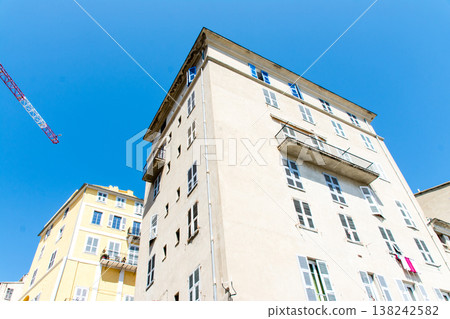 A pastel-colored building with blackout doors bathed in bright sunlight on the French island of Corsica in the Mediterranean Sea. A pastel-colored building with blackout doors bathed in bright sunlight on the French island of Corsica in the Mediterranean Sea. 138242582