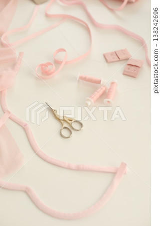 Flat lay composition with scissors and sewing supplies on the table. Crafting essentials for sewing projects with fabric, threads, and tools, ribbon tapes on white background. Flat lay composition with scissors and sewing supplies on the table. Crafting essentials for sewing projects with fabric, threads, and tools, ribbon tapes on white background. 138242696
