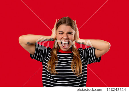 Woman reacts with frustration by blocking out noise or unwanted information. Stress, overload, conflict, workplace disagreement, rejection of opinions in business context. 138242814